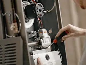 Furnace repair technician inspecting internal components and wiring in Loveland, CO