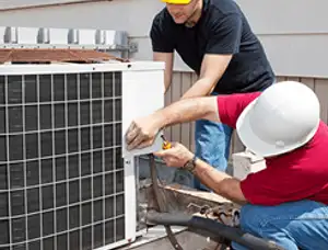 HVAC technicians repairing an outdoor AC unit on a rooftop in Loveland, CO