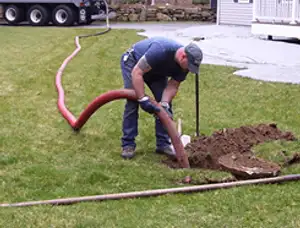 Septic pumping technician servicing a residential septic tank with a vacuum hose in Loveland, CO