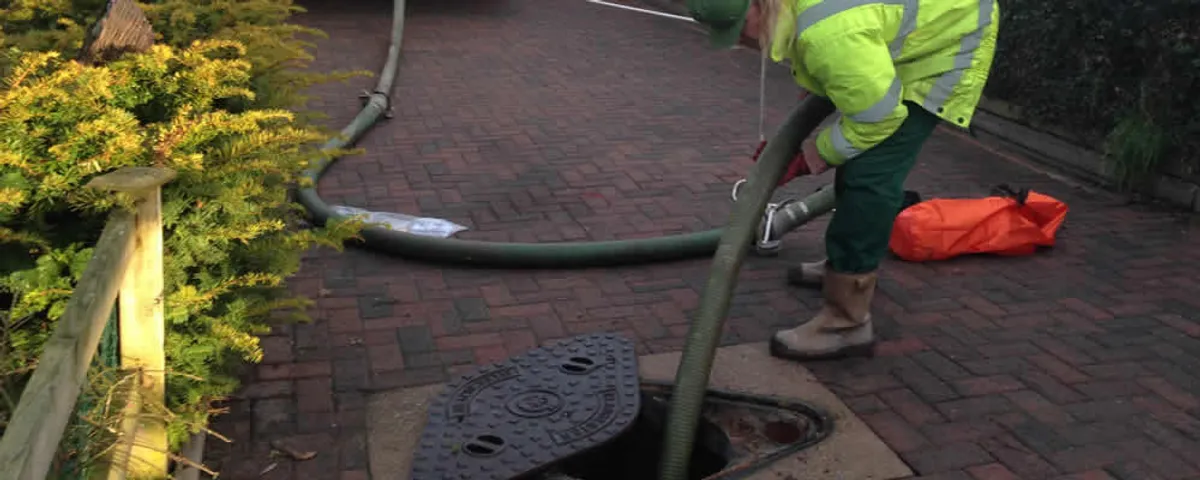 Septic tank cleaning technician servicing a septic tank with a vacuum hose in Loveland, CO